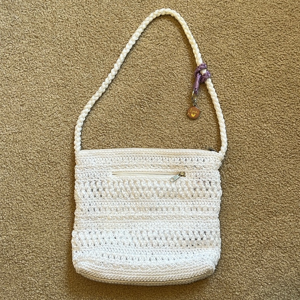 Lina white crocheted purse with purple accent.